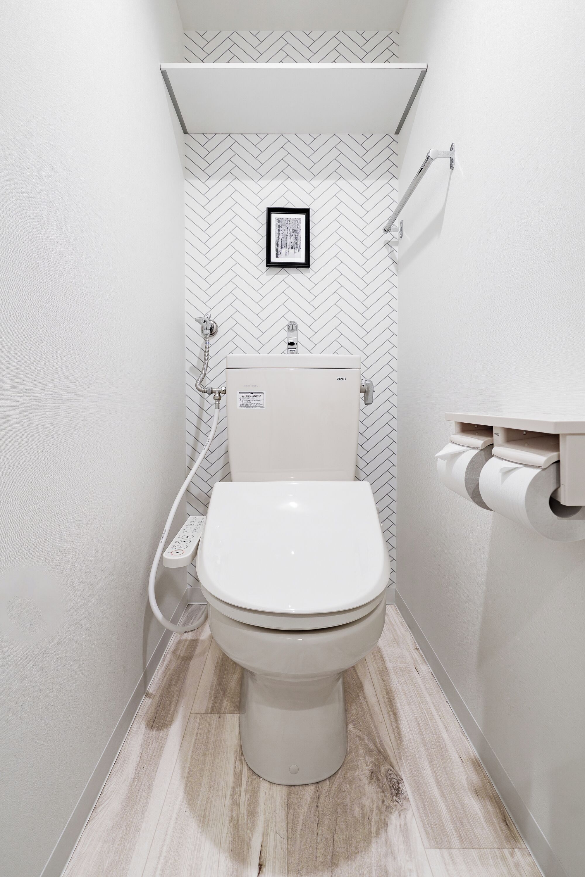 A modern bathroom with a white toilet, a shower with a handheld showerhead, and a toilet paper holder mounted on the wall.