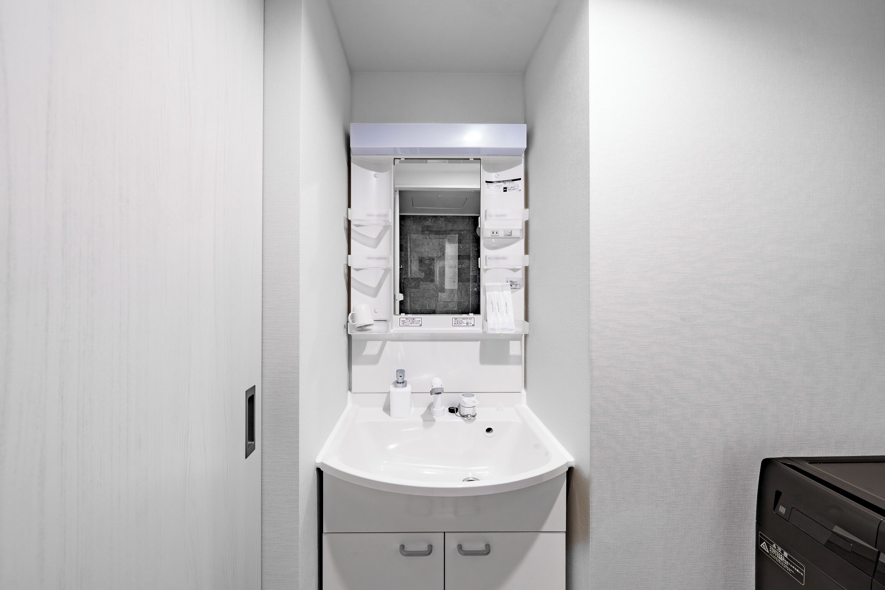 A small, modern bathroom with a white sink, a mirror, and a cabinet below.