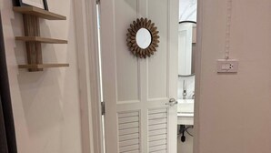 A hallway with a wooden floor, a door with louvered panels, a framed picture on a shelf, and a mirror on the wall. - 3BR Family Villa - 1 km to Chalong Pier with WiFi (Chalong)
