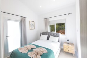 Une chambre à coucher avec un lit, une table de chevet, une fenêtre et une porte.