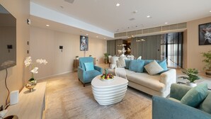 Ein modernes Wohnzimmer mit einer Couch, Sesseln, einem Couchtisch und einem Fernseher.