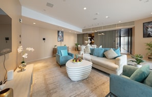 Ein modernes Wohnzimmer mit einer Couch, Sesseln, einem Couchtisch und einem Fernseher.