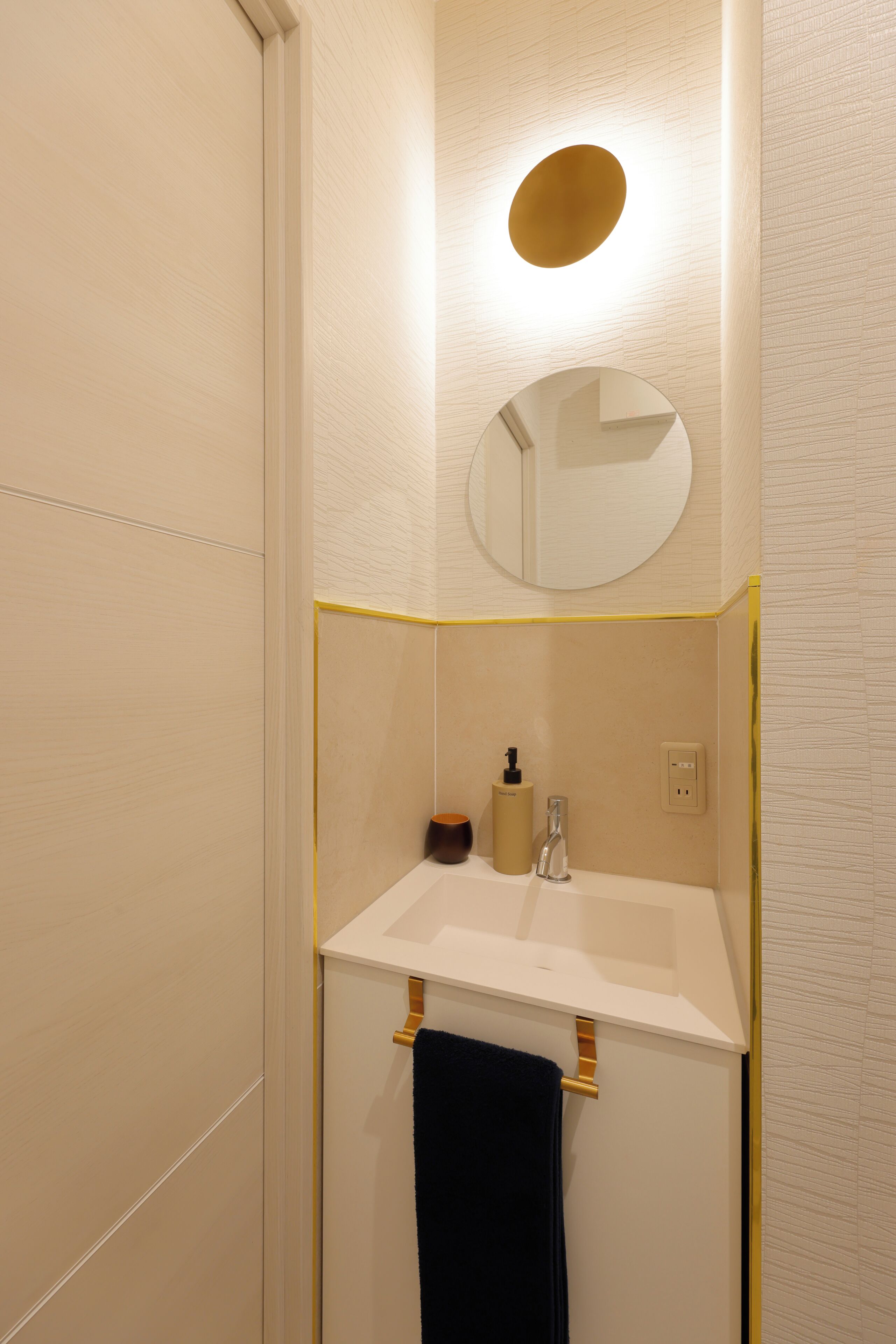 A bathroom with a white sink, a mirror, a towel rack, and a soap dispenser.