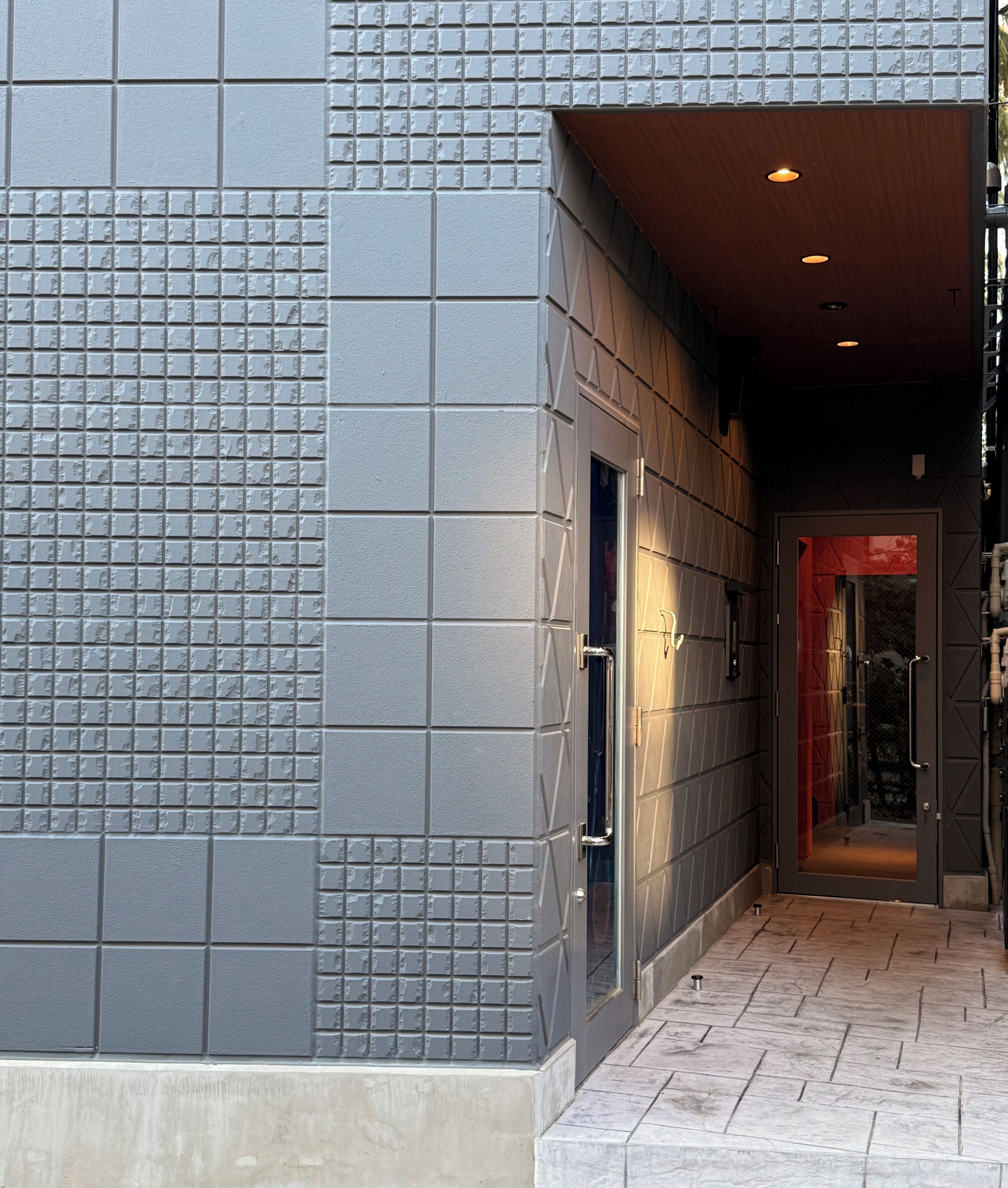 A hallway with a tiled wall, a wooden door, and a tiled floor.