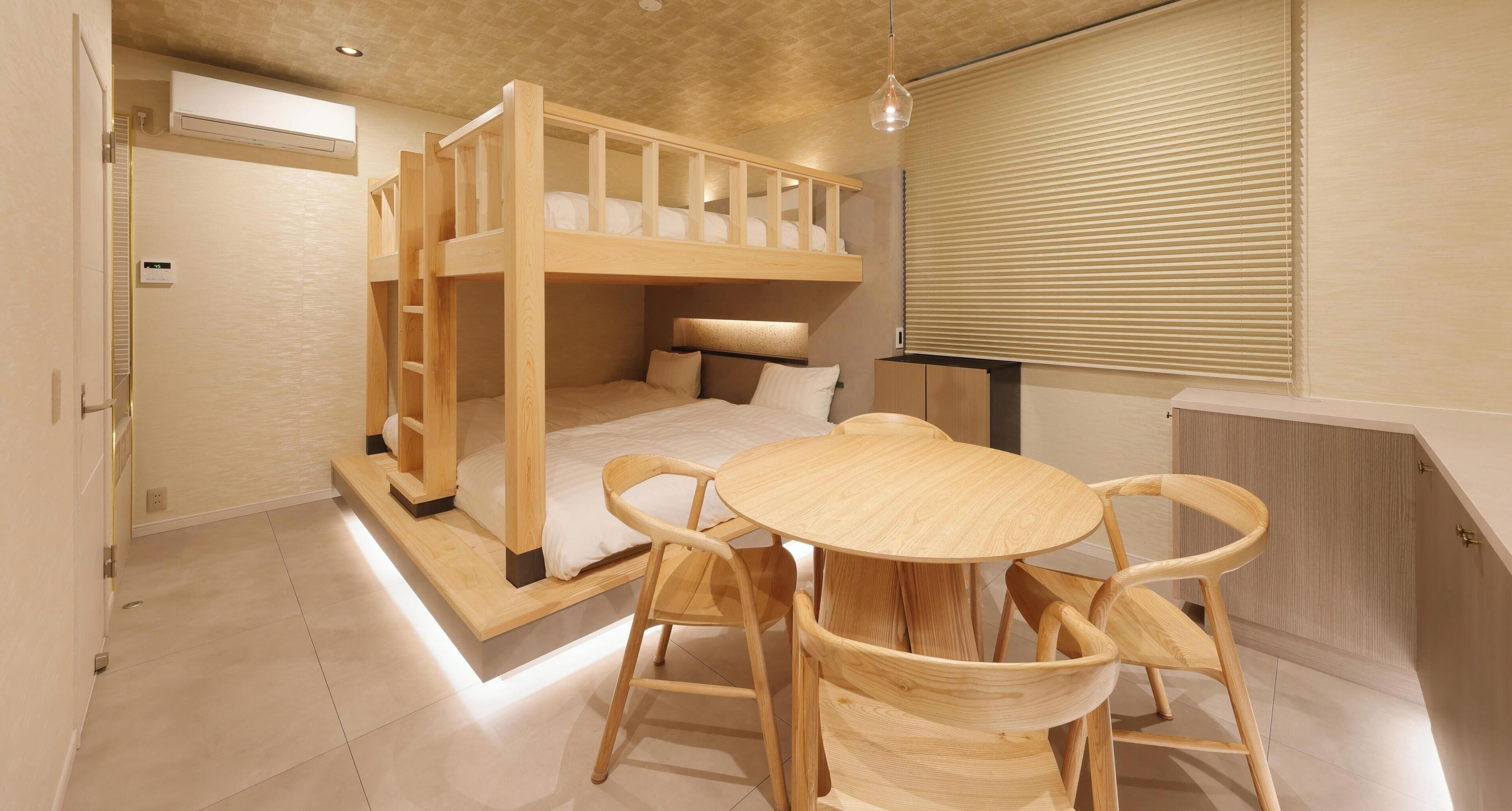 A bunk bed with a desk and chairs, a window with blinds, and an air conditioning unit.