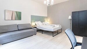 Ein modernes Schlafzimmer mit einem Bett, einem grauen Sofa, einem Schreibtisch und einem Kleiderschrank.