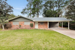 A single-story house with a brick facade, a covered garage, and a well-maintained lawn.