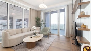 A modern living room with a beige sofa, a round coffee table, and a chair. There is a large window with a view of the city. - Vogue | Al Wasl 1 Residence near World Trade Centre (Dubai)