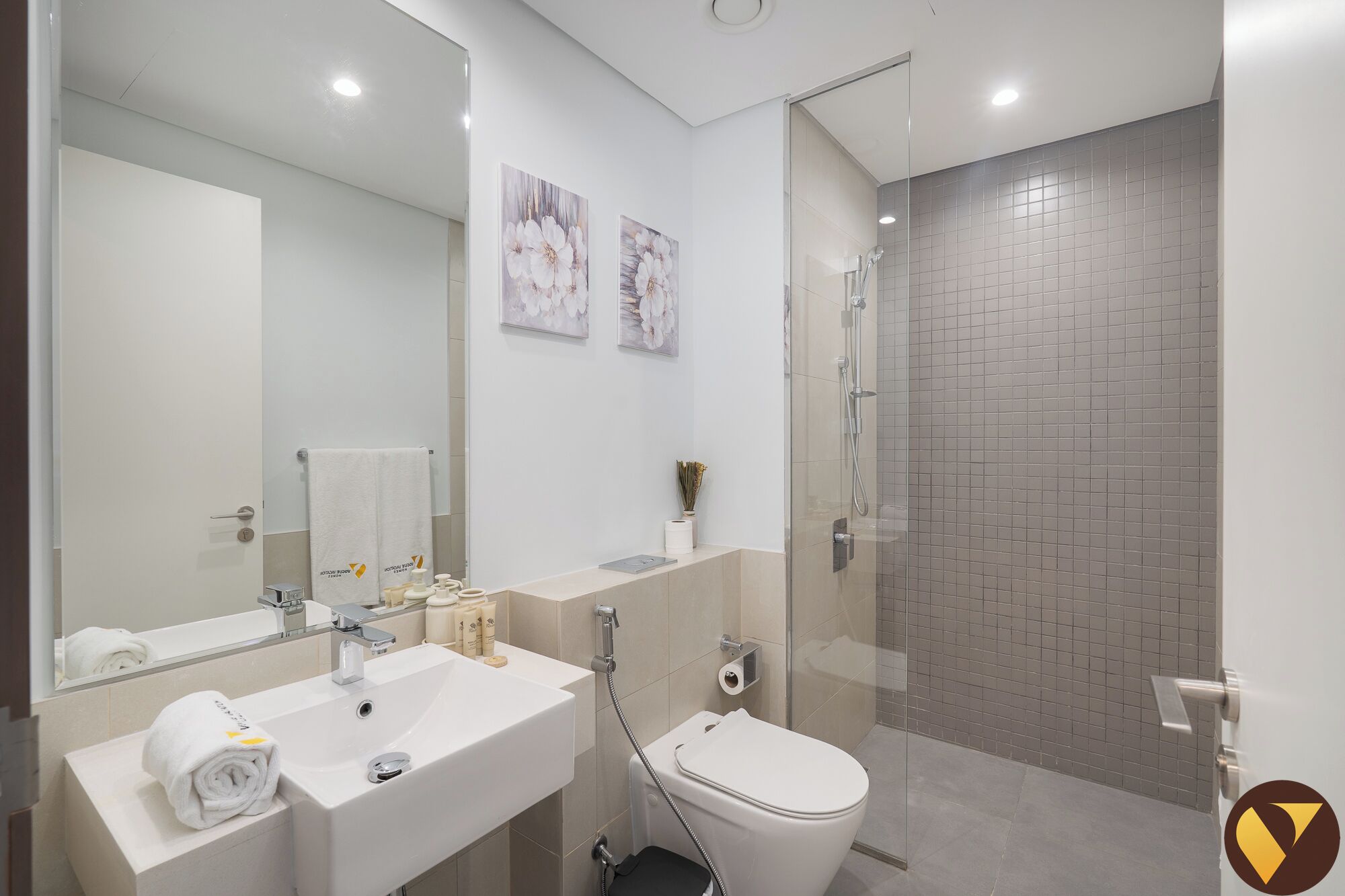 Un baño moderno con un espejo grande, un lavabo, un inodoro y una zona de ducha.