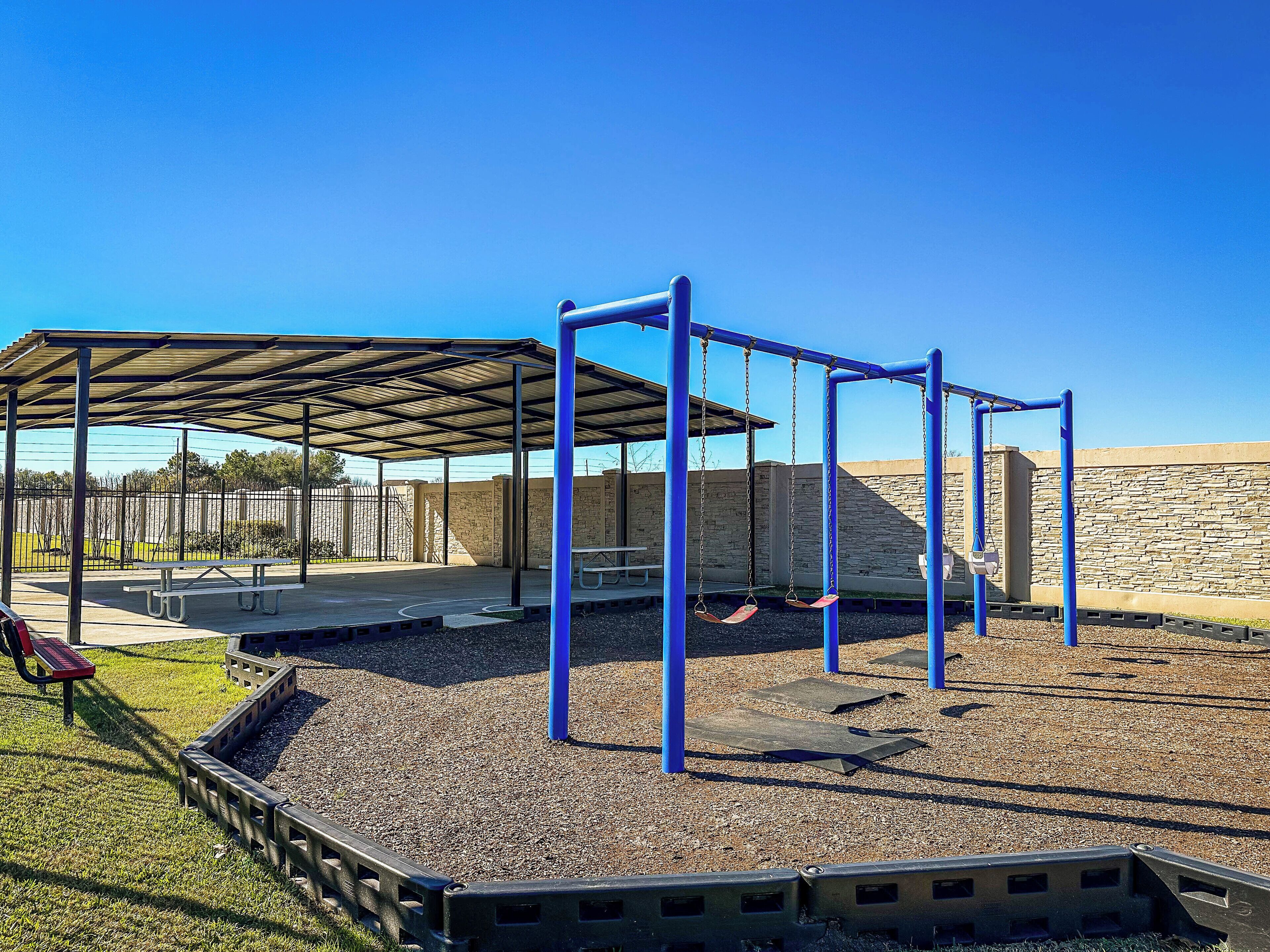 Ein Spielplatz mit Schaukeln und einer überdachten Sitzgelegenheit.