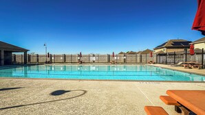 Una piscina con agua cristalina azul, rodeada por una cerca y bancos.