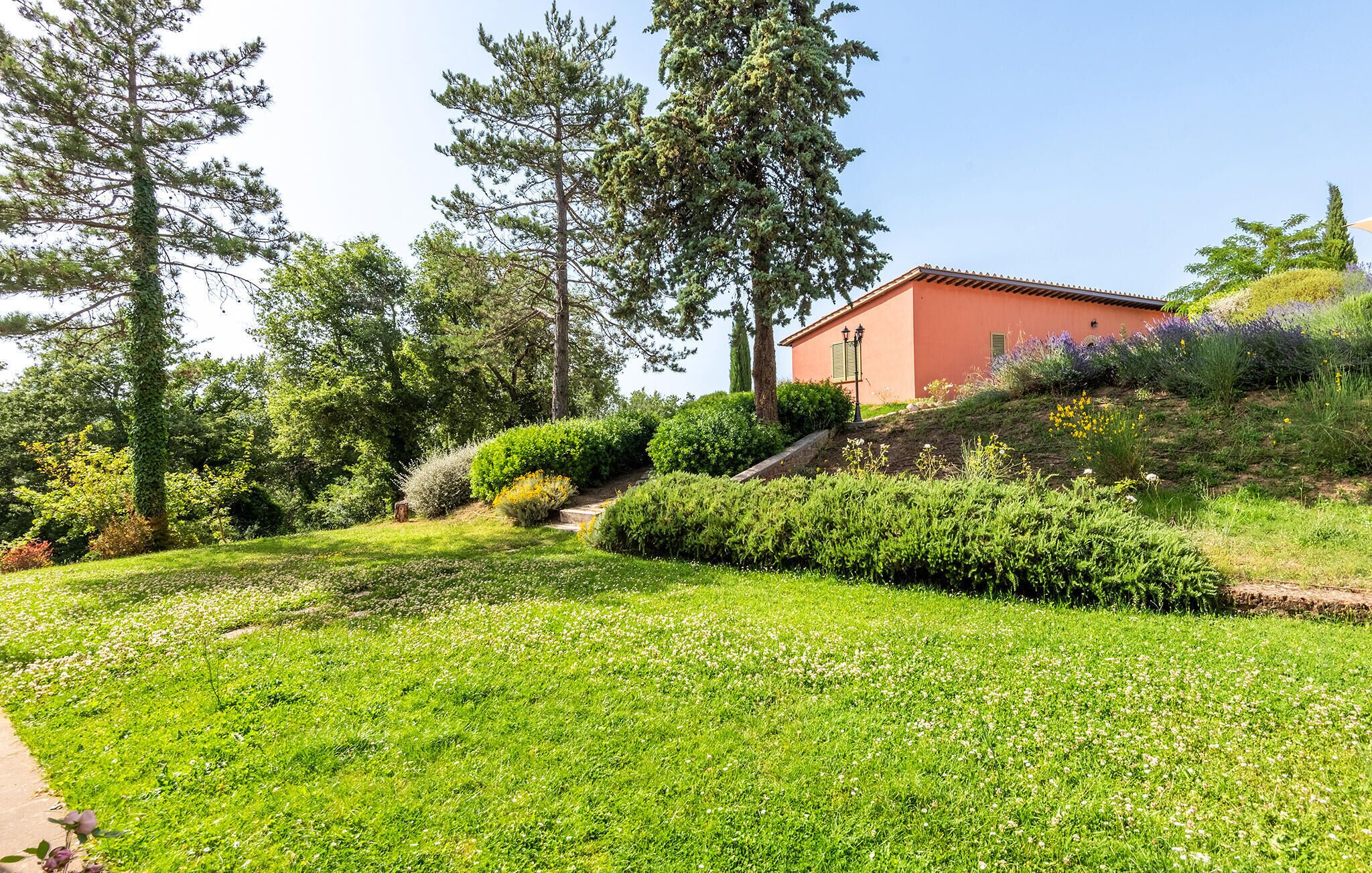 Une maison à la façade rouge, entourée d’une végétation luxuriante et d’un jardin bien entretenu.