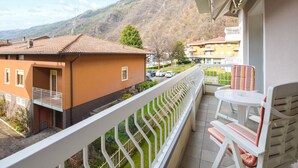 A balcony with a white railing, a small table, and a striped chair.