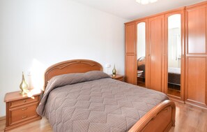 A bedroom with a wooden bed, a nightstand with a lamp, and a wardrobe. - Gorgeous apartment in Ponte Caffaro with WiFi (Ponte Caffaro)