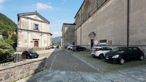 A narrow street with parked cars and a building with a sign reading "IHS LAURENTUS".