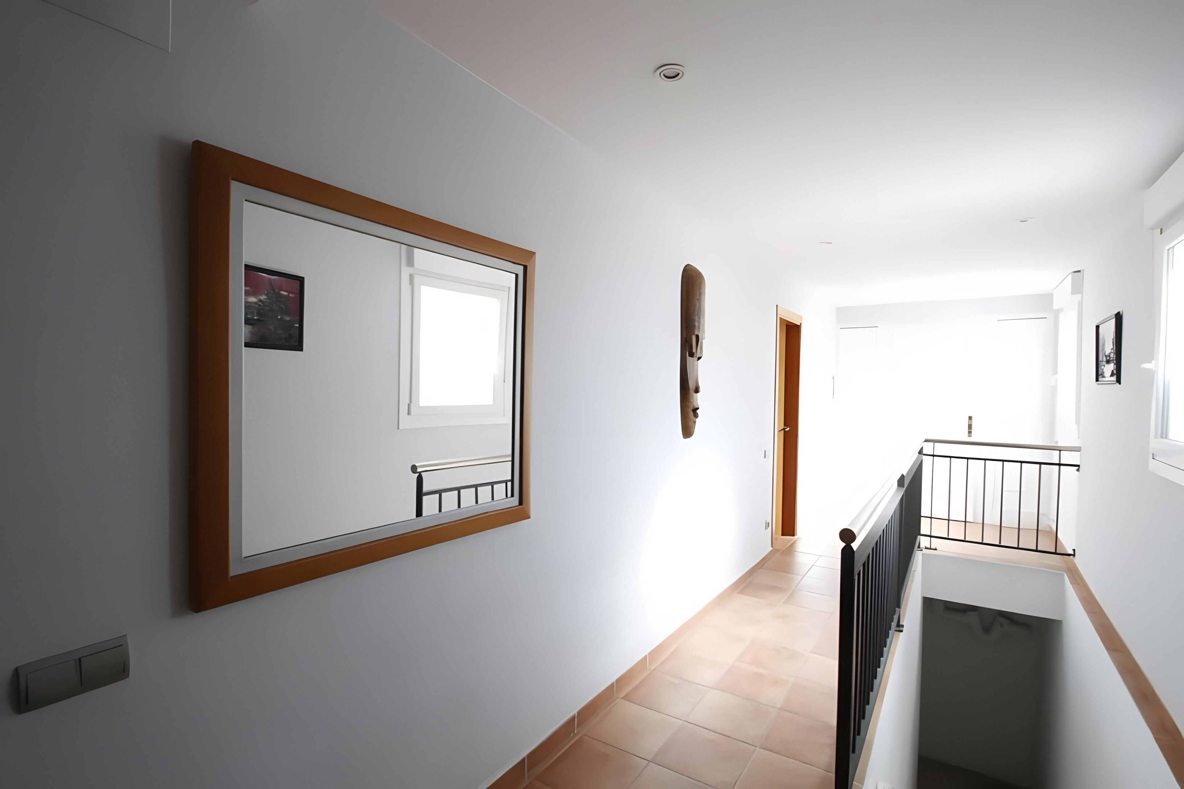 A hallway with a large framed picture, a door, and a staircase.