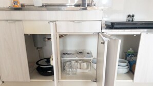 Uma cozinha compacta com máquina de lavar louça embutida, pia e área de armazenamento com pratos e utensílios.