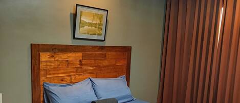 A neatly made bed with a wooden headboard, a blue mattress, and pillows.