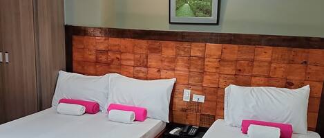 Two single beds with wooden headboards, white linens, and pink accents.