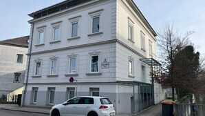 A white building with a car parked in front.