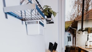 A kitchen with a wooden countertop, a white mug, a knife block, and a plant on a shelf.