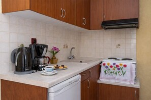 A kitchen with wooden cabinets, a coffee maker, a kettle, a sink, and a stove.