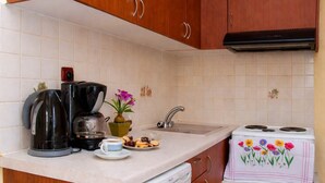A kitchen with wooden cabinets, a coffee maker, a sink, and a stove.