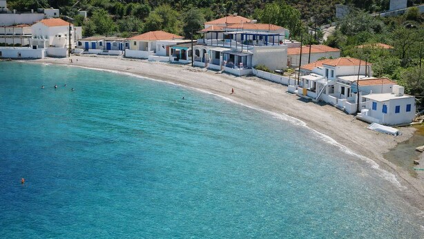 Una zona costanera amb edificis blancs, una platja sorrenca i aigua turquesa.