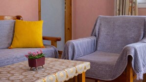 Una habitació amb dos sofàs, un amb coixí groc, i una taula amb mantell estampat.