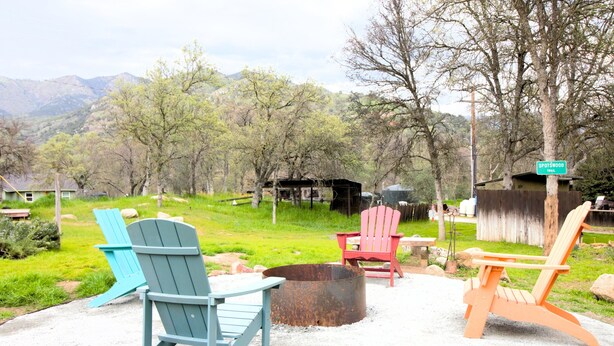 A campsite with three Adirondack chairs, a fire pit, and a sign indicating the name 'Spotswood Trail'. - Deer Hollow Cabin - A family-friendly 3-bedroom cabin in charming Three Rivers (Three Rivers)
