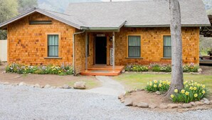 A two-story brick house with a front porch, a welcome sign, and a gravel driveway. - Deer Hollow Cabin - A family-friendly 3-bedroom cabin in charming Three Rivers (Three Rivers)