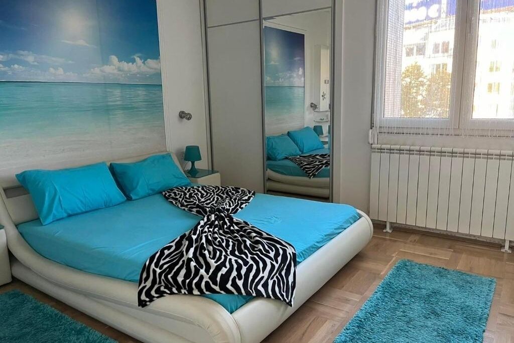 Une chambre à coucher avec un lit, un miroir, une fenêtre et une fresque murale.
