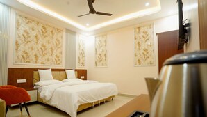 A modern hotel room with a large bed, a ceiling fan, and a coffee machine.
