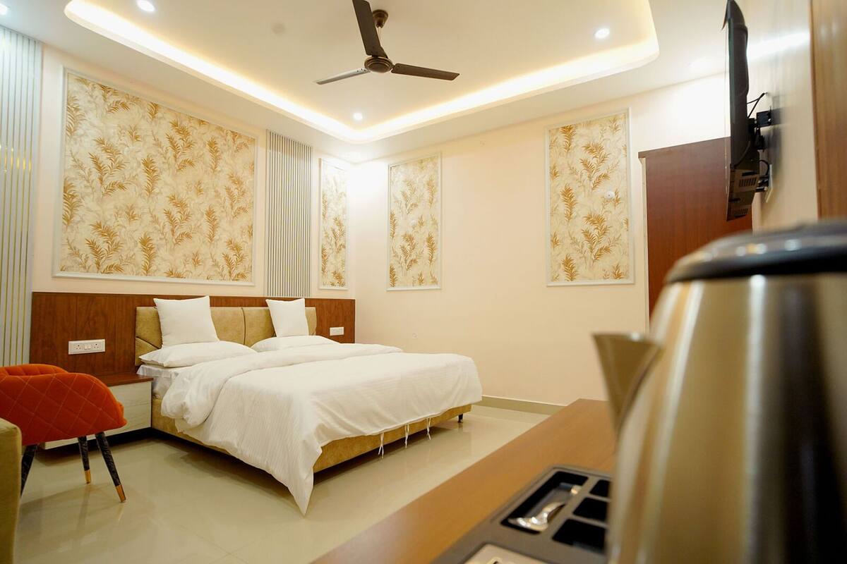 A modern hotel room with a large bed, a ceiling fan, and a coffee machine.