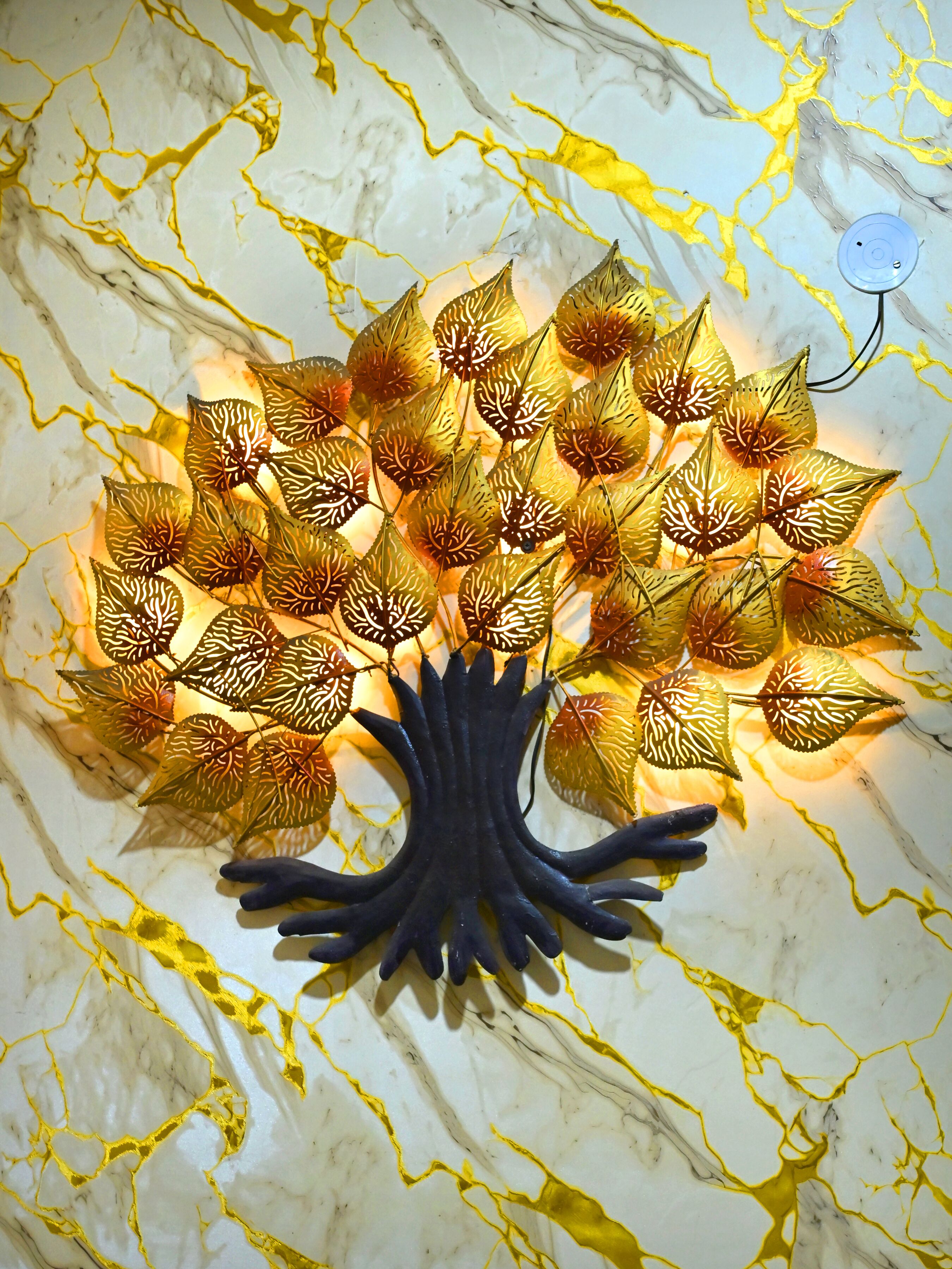 A decorative tree with leaves on a marble wall.