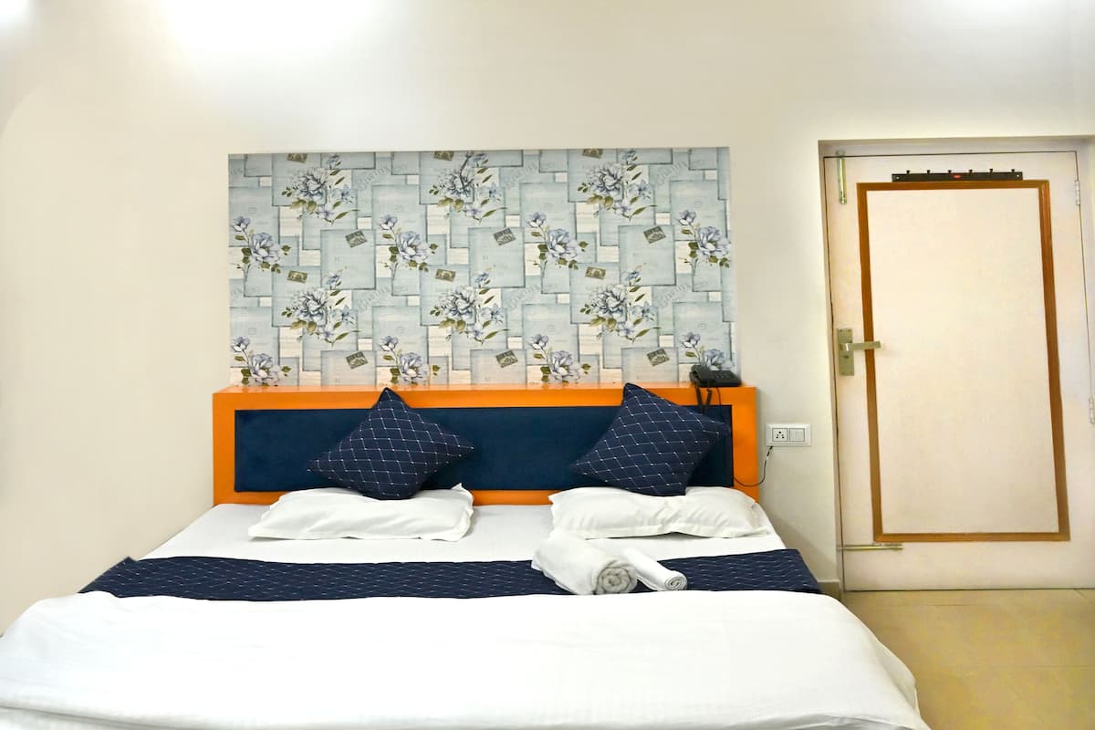 A neatly made bed with a headboard, a ceiling fan, and a door to the right.