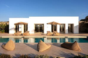 Une villa moderne dotée d’une piscine, d’un espace extérieur aménagé et offrant une vue dégagée sur le paysage environnant.