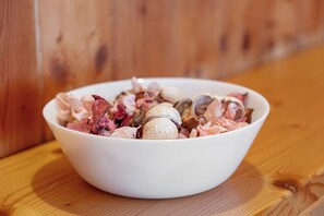 A white bowl filled with various nuts and dried fruits on a wooden surface.