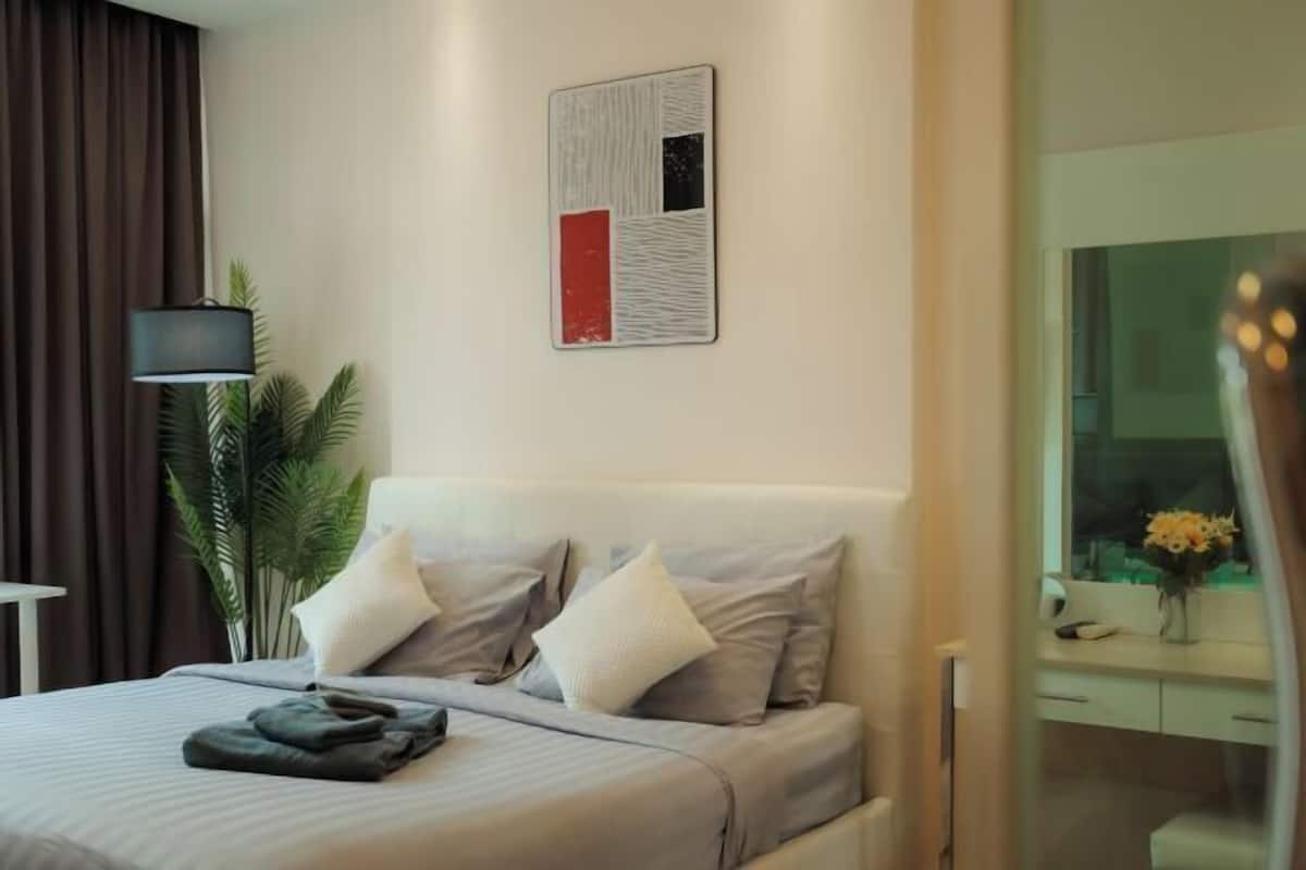 Ein modernes Schlafzimmer mit einem Bett, Kissen, einem Nachttisch, einer Lampe und einem Wandbild.