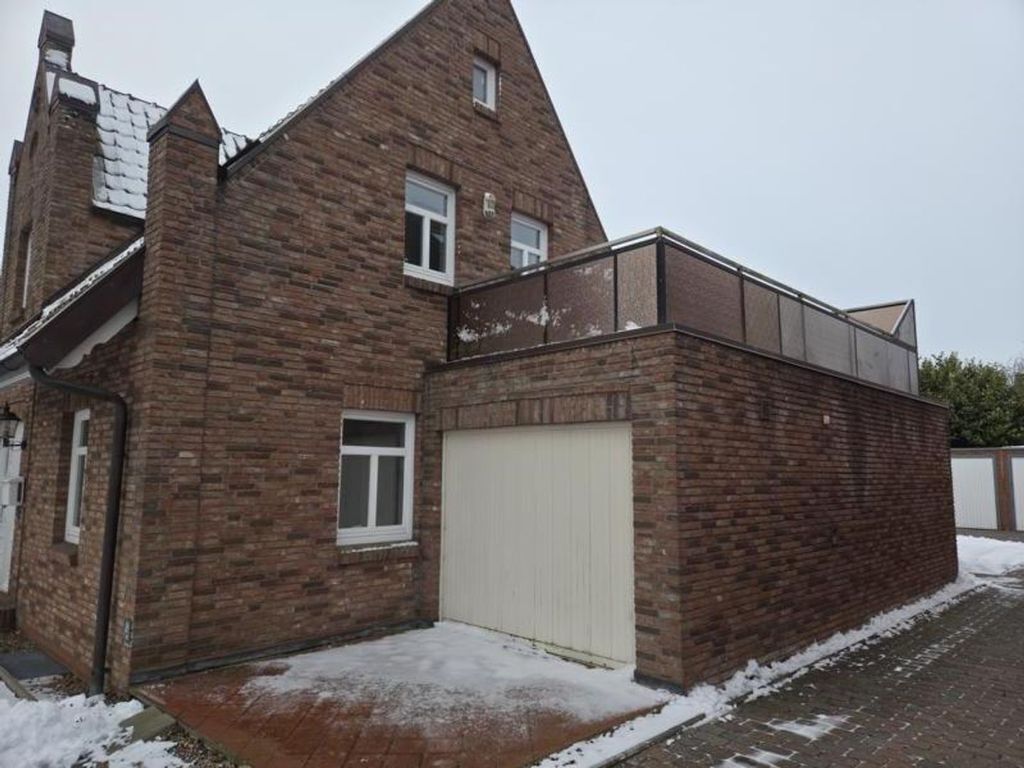A two-story brick building with a garage door, a small window, and a balcony.
