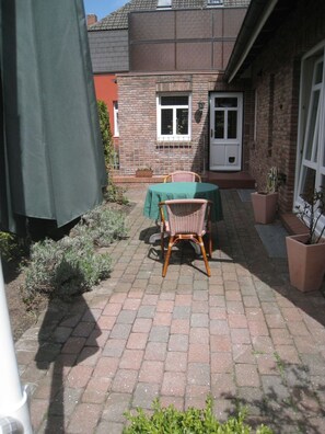 A patio with a table and chairs, a brick wall, and a door. - Plenty of space for the whole family - North Sea vacation at Haus Küstenwind - House (Wyk auf Föhr)