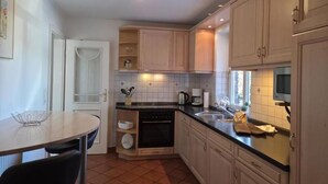 A compact kitchen with white cabinets, a black countertop, and a tiled backsplash. - Plenty of space for the whole family - North Sea vacation at Haus Küstenwind - House (Wyk auf Föhr)