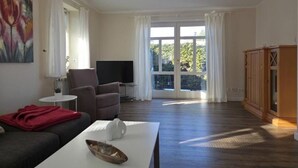 A living room with a sofa, a coffee table, a TV, and a cabinet. - Plenty of space for the whole family - North Sea vacation at Haus Küstenwind - House (Wyk auf Föhr)