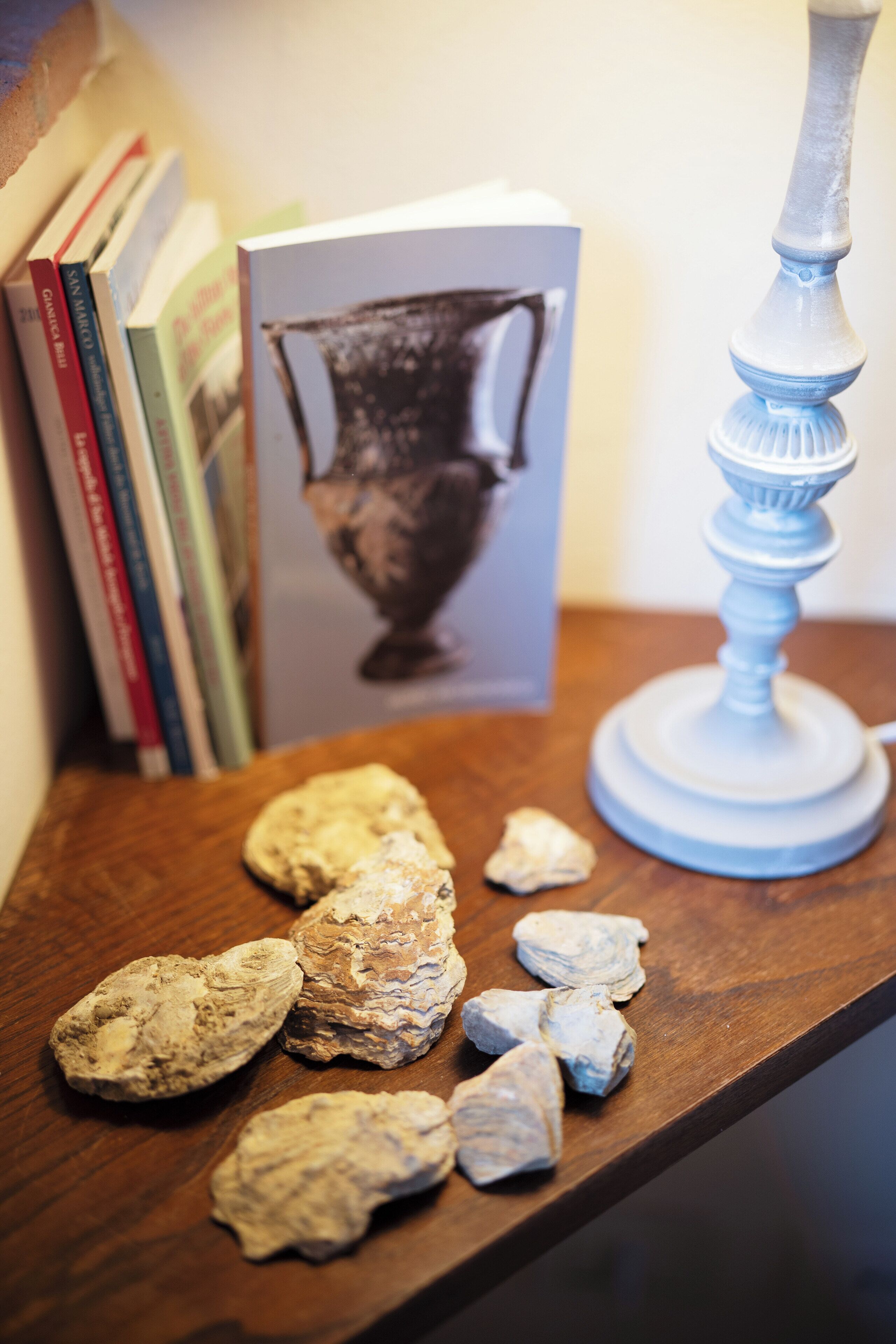 Ein hölzernes Regal mit Büchern, einer Vase und Steinen.