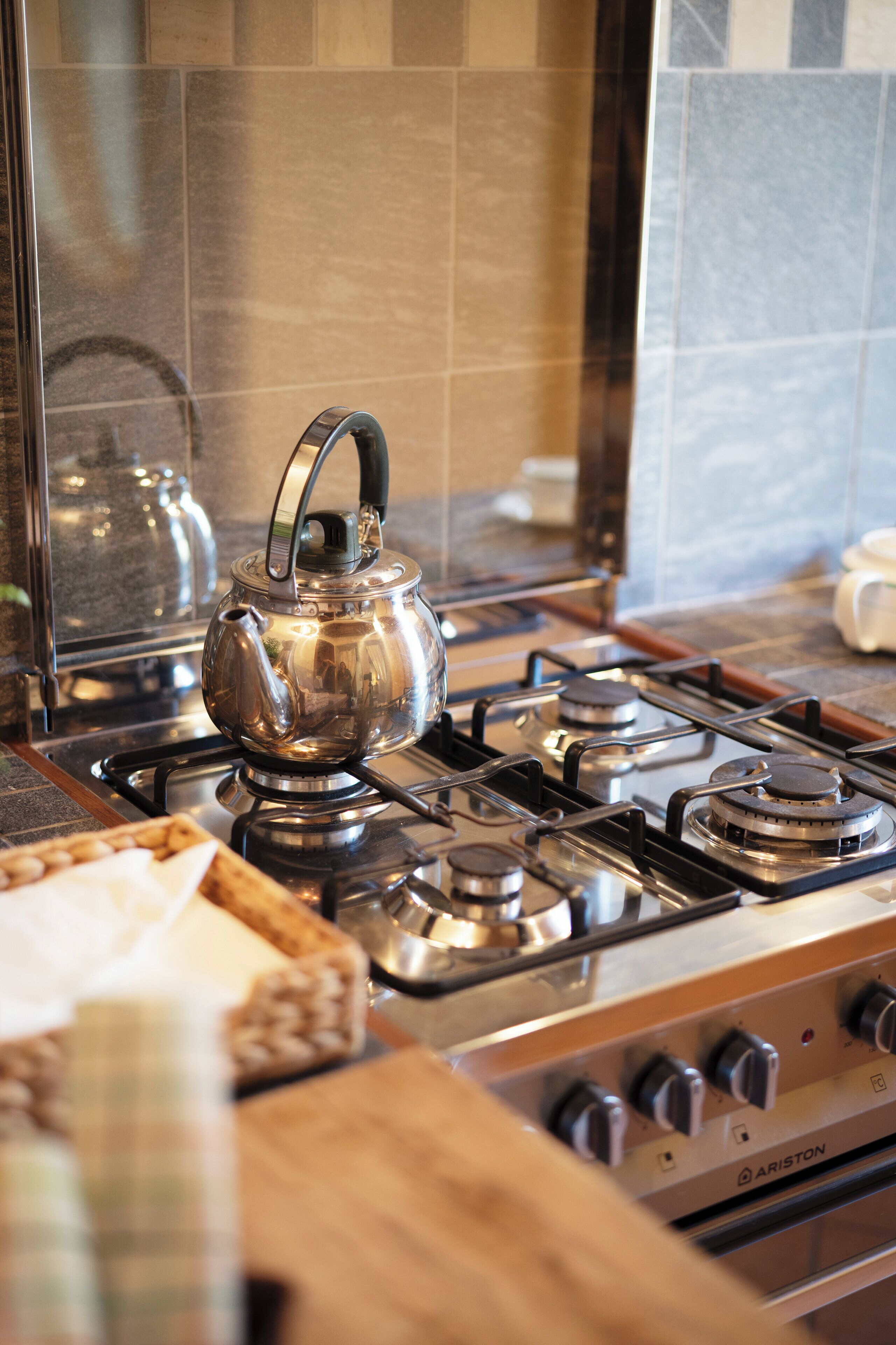 Une cuisine équipée d’une cuisinière en acier inoxydable, d’une bouilloire et d’une planche à découper en bois.