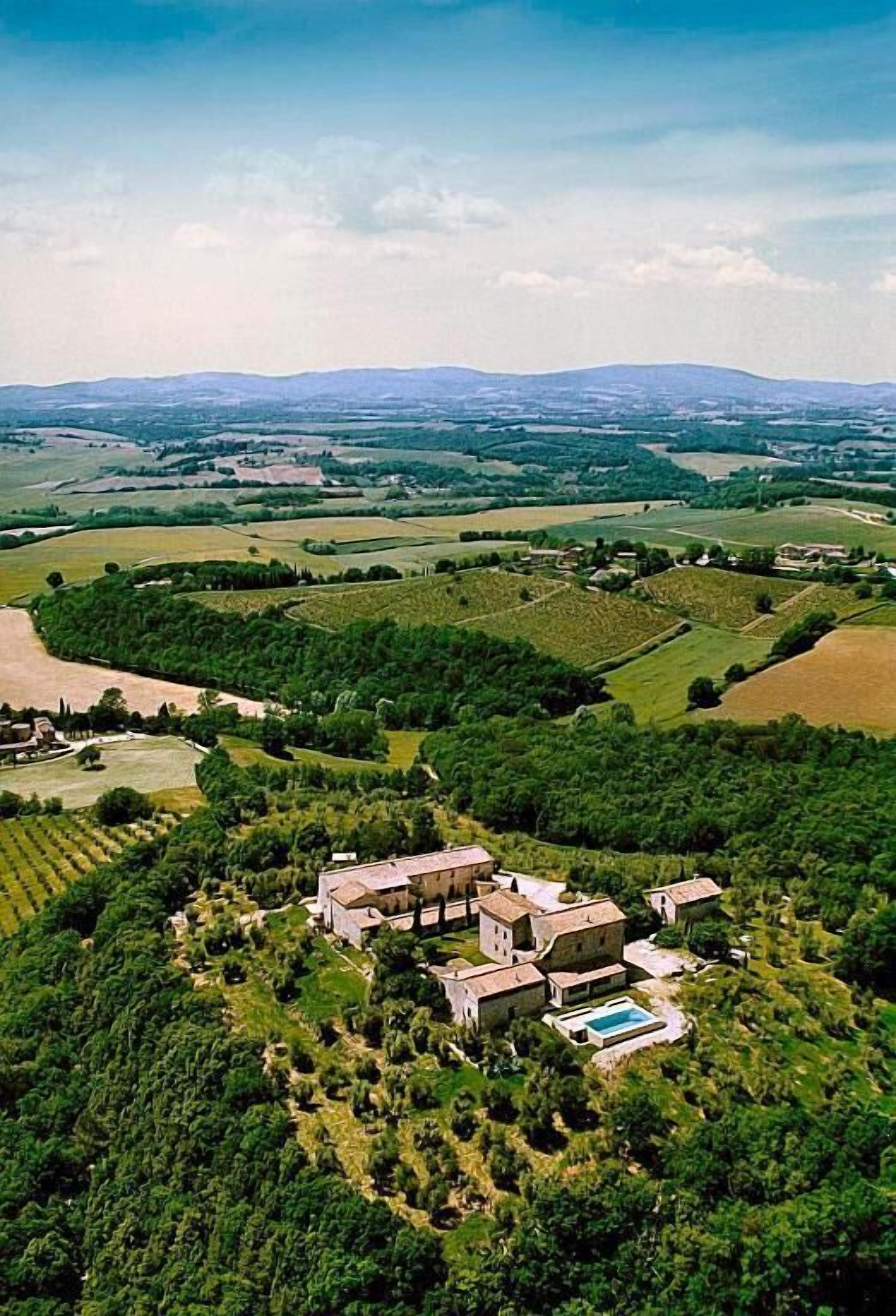 Vista aérea de una finca campestre con varias construcciones, una piscina y campos verdes circundantes.