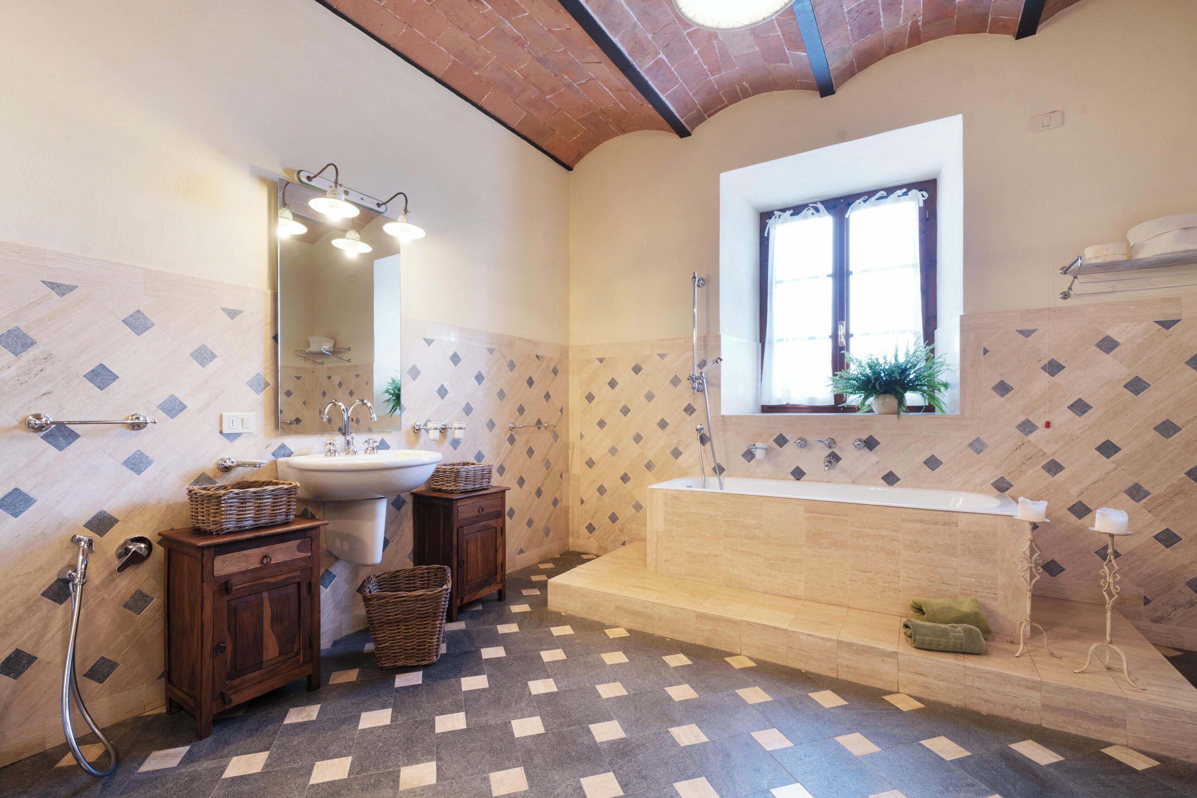 A bathroom with a large bathtub, a sink, a mirror, and a window.