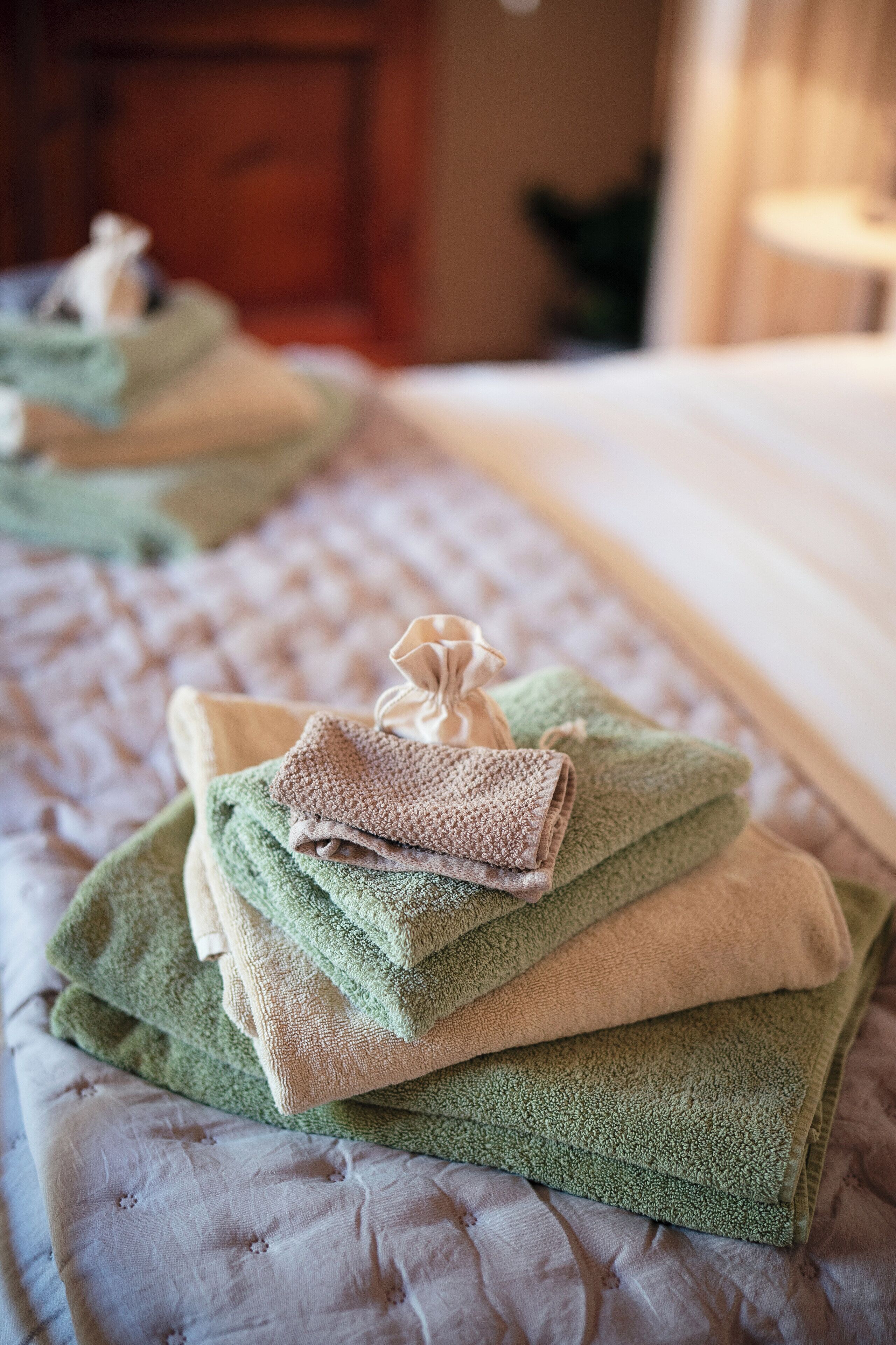 A neatly made bed with folded towels in various colors.