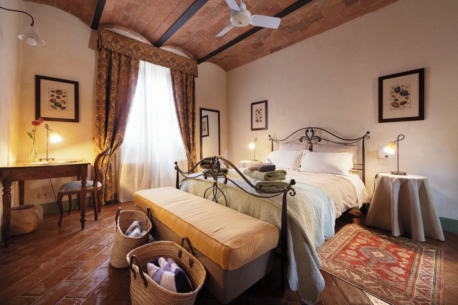 A cozy bedroom with a bed, bedside tables, a desk, and a chair.