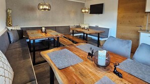 Een moderne eetruimte met houten tafels en banken, een grote hanglamp en een houten wand.